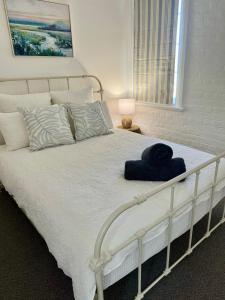 Un dormitorio con una cama blanca con un sombrero azul. en The Gallipoli Flat, en Narrabri