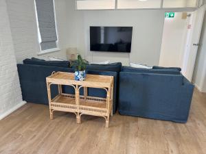 a living room with a blue couch and a table at The Gallipoli Flat in Narrabri