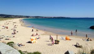 Grupa ludzi na plaży, blisko wody w obiekcie A Apartamentos Diego w mieście O Grove