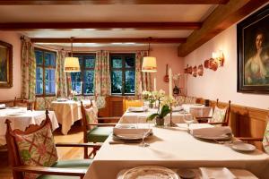 a dining room with tables and chairs and windows at Relais & Châteaux Hotel Tennerhof in Kitzbühel
