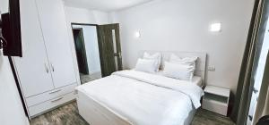 um quarto branco com uma cama com lençóis e almofadas brancos em Cosy apartment Fagaras em Făgăraş
