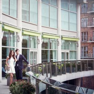 una sposa e uno sposo che camminano lungo un ponte di fronte a un edificio di The Lowry Hotel a Manchester