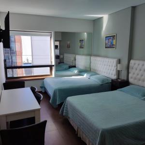 een hotelkamer met vier bedden en een raam bij Buenos Aires Center Apart in Buenos Aires