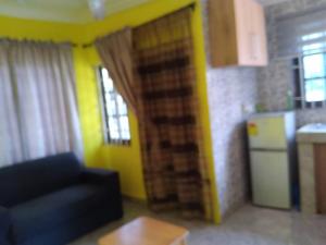 sala de estar con sofá azul y cocina en Abokobi Cosy Home en Accra