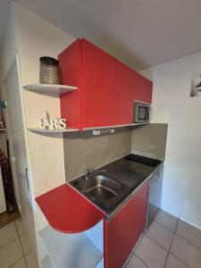 a small kitchen with red cabinets and a sink at Appartement Saint cyprien plage in Saint-Cyprien