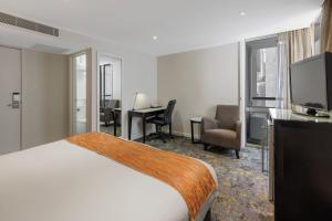 Habitación de hotel con cama, escritorio y TV. en Hotel Grand Chancellor Melbourne en Melbourne