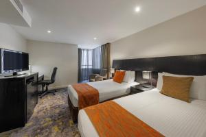 Cette chambre comprend 2 lits et une télévision à écran plat. dans l'établissement Hotel Grand Chancellor Melbourne, à Melbourne