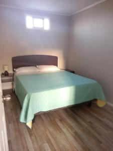 um quarto com uma cama com uma colcha verde em departamentos mirador 2 piso em Caldera