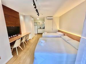 Habitación con 2 camas, escritorio y TV. en BSB Stay Flats Particulares - SHN, en Brasilia