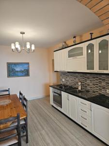 a kitchen with white cabinets and a table and a microwave at Villa Dario in Vlorë