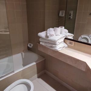 een badkamer met een ligbad, een toilet en handdoeken bij Buenos Aires Center Apart in Buenos Aires