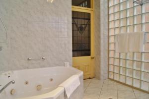 bañera blanca en el baño con puerta en Fire Station Inn, en Adelaida