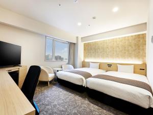 a hotel room with two beds and a flat screen tv at Daiwa Roynet Hotel Gifu in Gifu