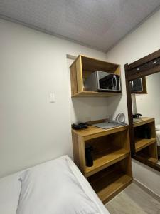 Alojamiento turístico Keniant's في سان أندريس: غرفة صغيرة بها سرير وميكروويف