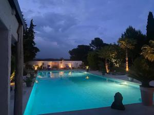una gran piscina de agua azul por la noche en DOMAINE DE LA SOURCO - Villa, Maisons & Chalet, Magnifique Havre De Paix En Provence en Trans-en-Provence