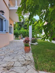 a stone walkway with a pot of flowers in a yard at DIMITRA STUDIOS in Lefkada Town