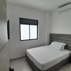 a white bedroom with a bed and a window at Aw Hotel Puerta de San Cayetano in Cali