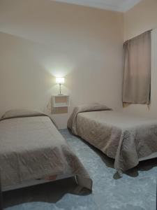 a bedroom with two beds and a lamp on the wall at 'Complejo Sol Andino" in San Fernando del Valle de Catamarca
