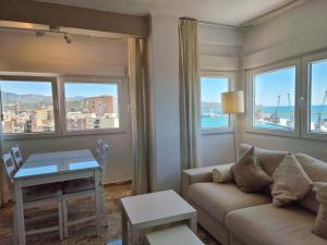 uma sala de estar com um sofá, uma mesa e janelas em VISTAMALAGA em Málaga