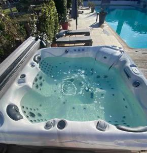 a bath tub with water in it next to a pool at DOMAINE DE LA SOURCO - Villa, Maisons & Chalet, Magnifique Havre De Paix En Provence in Trans-en-Provence