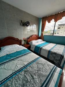two beds in a room with a window at Kanoas Hostal in Puyo
