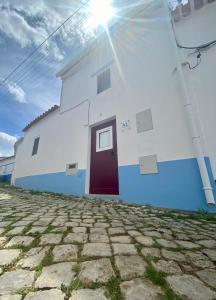 a white and blue building with a red door at Casa do Serro de Lá in Santa Clara-a-Nova