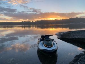 a boat sitting in the water at sunset at Pukehina Estuary Sunset Views Townhouse & Studio in Pukehina +5 photos