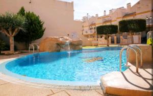 a large swimming pool with a waterfall in a building at Adosado mediterráneo in Orihuela Costa