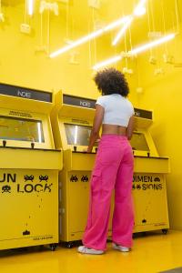 Una donna con i pantaloni rosa in piedi al bancone di Indie Universe Creative Hotel a Medellín