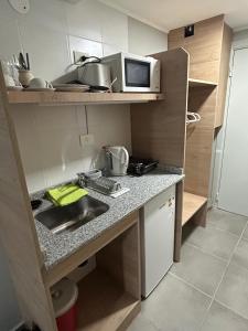 Una pequeña cocina con fregadero y microondas. en Monoambiente M670, en San Carlos de Bariloche