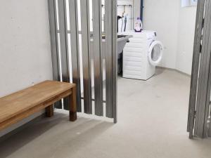 une cellule pénitentiaire avec un lave-linge et un banc dans l'établissement Falken Suites TOP 3, à Kaprun