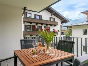 - une table en bois avec des verres à vin et des fleurs sur le balcon dans l'établissement Falken Suites TOP 3, à Kaprun