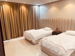 2 Betten in einem Hotelzimmer mit Vorhängen in der Unterkunft جودة الحياة in Al Kharj