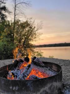 a fire pit on the beach next to a lake at Spot Caché - Waterfront - Water sports included! in Papineauville