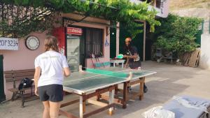 eine Person, die neben einer Tischtennisplatte steht in der Unterkunft Oasis Hostel in Himarë