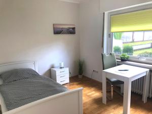 een slaapkamer met een bed, een bureau en een raam bij Gästehaus Stadthagen in Stadthagen