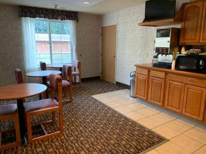 a room with a kitchen with a table and a microwave at Budget Host Inn in Allegan