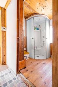 a bathroom with a shower and a wooden floor at Obasute Guesthouse Nakaraya in Chikuma