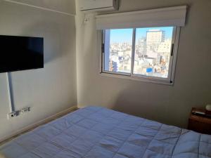 ein Schlafzimmer mit einem Bett und einem großen Fenster in der Unterkunft Rooftop Sunlight Movistar Arena in Buenos Aires