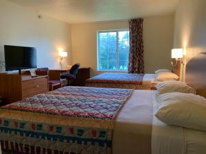 a hotel room with two beds and a television at Budget Host Inn in Allegan