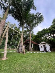 a house with two palm trees and a small shack at Familien Haus Pousada in Pomerode