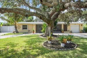 a house with a tree in a yard at Coastal Chic Home, Walk to Beach in Cocoa Beach