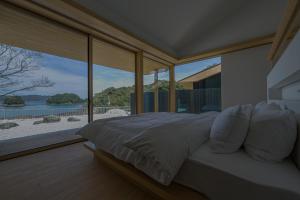 Un dormitorio con una cama con vistas a la playa. en 星降る別邸WANASA, en Kannoura