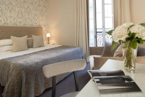 a bedroom with a bed and a table with a vase of flowers at Le Nemours Rennes in Rennes