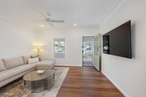 a living room with a couch and a tv on a wall at The Gumnut Cottage in Wickham