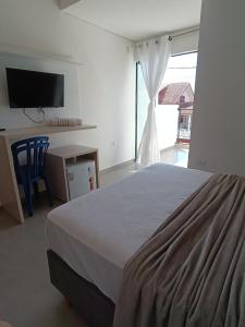 um quarto com uma cama, uma secretária e uma televisão em Residencial Mar Azul-suíte 12 em Pontal do Paraná