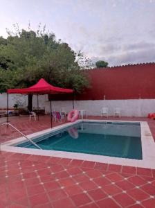 basen z czerwonym parasolem i czerwonym budynkiem w obiekcie Casa de la Amistad w mieście Areguá