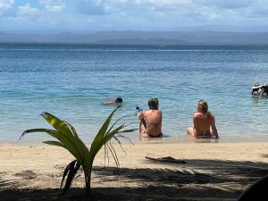 un grupo de personas en el agua en la playa en Dolphin Blue Paradise en Bocas Town