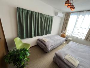 a bedroom with two beds and a green chair at N's Home - 南名古屋駅一軒家 - 8 in Nagoya