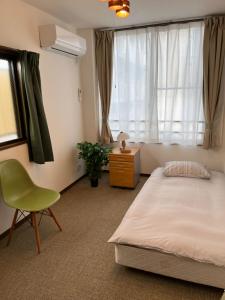 a bedroom with a bed and a chair and a window at N's Home - 南名古屋駅一軒家 - 8 in Nagoya